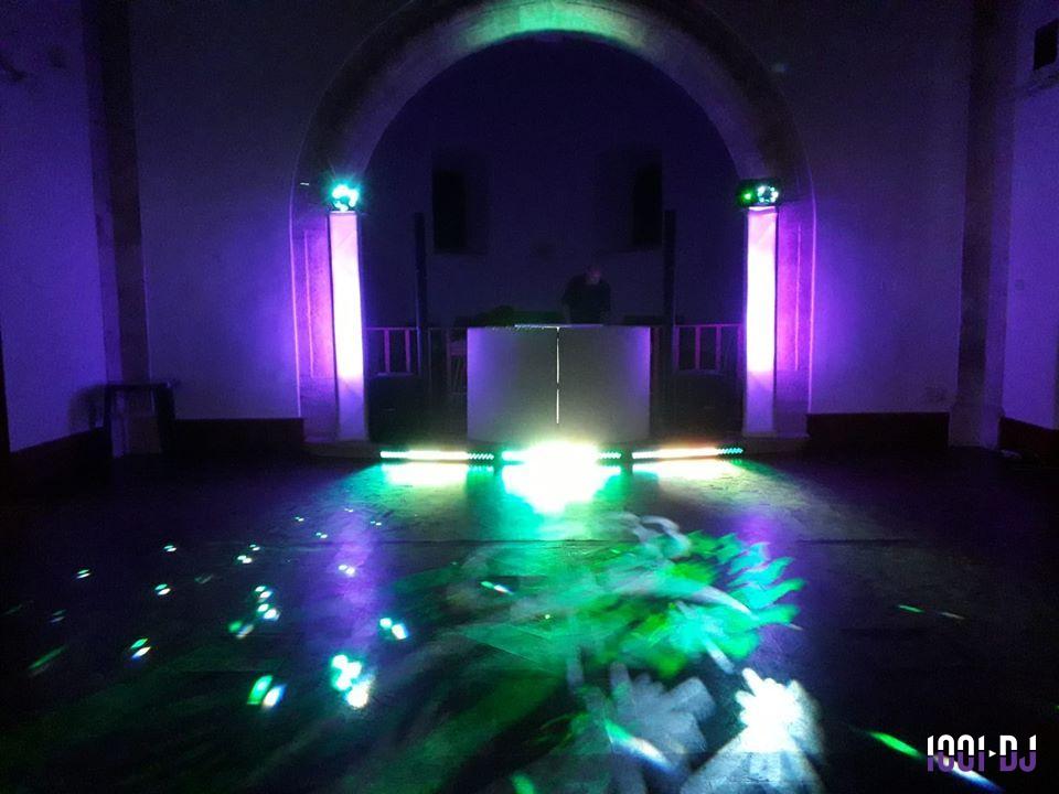 Je ne sais pas qui est sur cette image, mais elle montre une scène de soirée avec des lumières colorées et un DJ en arrière…