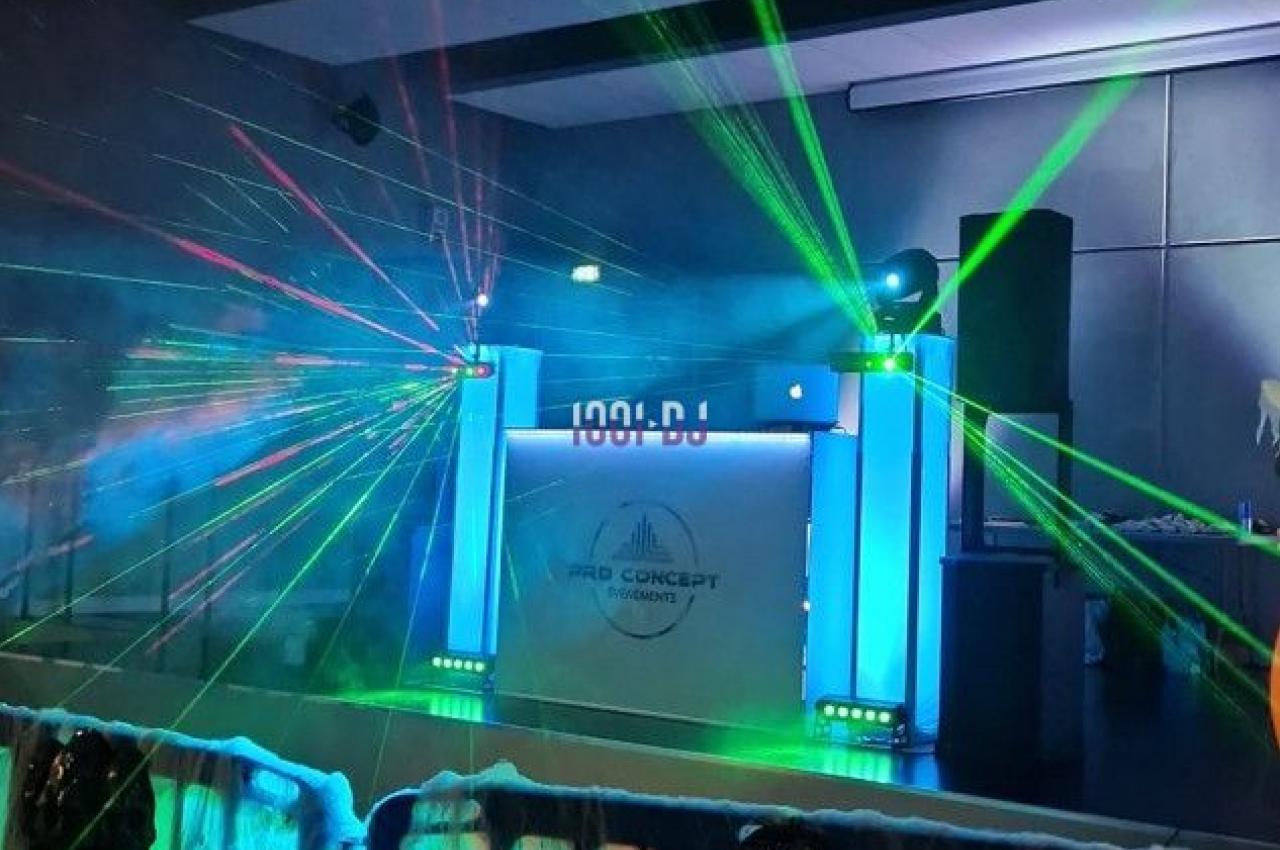 Jeu de lumières colorées et lasers projetés sur une scène avec une barrière décorée de toiles d'araignée.