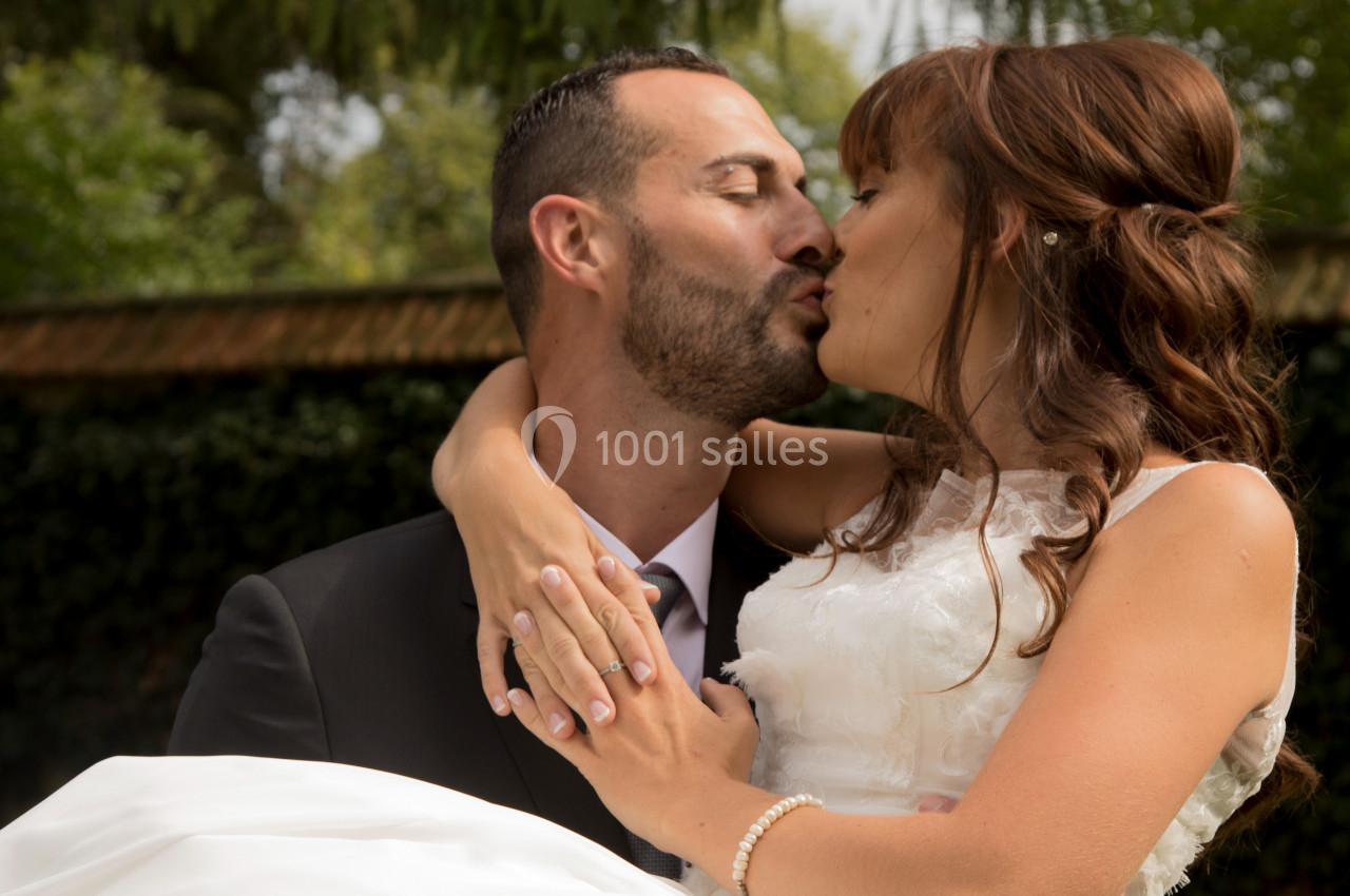 Un couple en tenue de mariage s'embrasse tendrement dans un jardin verdoyant.
