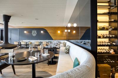 Façade moderne d'un hôtel Mercure avec des voitures circulant devant, entouré d'arbres et d'un ciel partiellement nuageux.