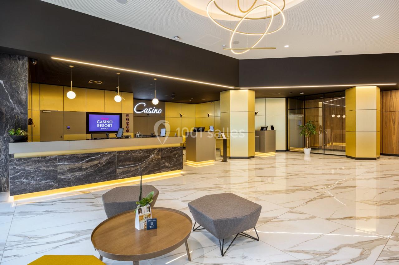 Hall d'accueil moderne avec comptoirs en marbre, sol en carrelage brillant, éclairage design et mobilier minimaliste.