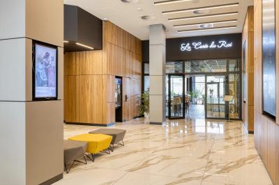 Façade moderne d'un hôtel Mercure avec des voitures circulant devant, entouré d'arbres et d'un ciel partiellement nuageux.