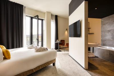 Façade moderne d'un hôtel Mercure avec des voitures circulant devant, entouré d'arbres et d'un ciel partiellement nuageux.