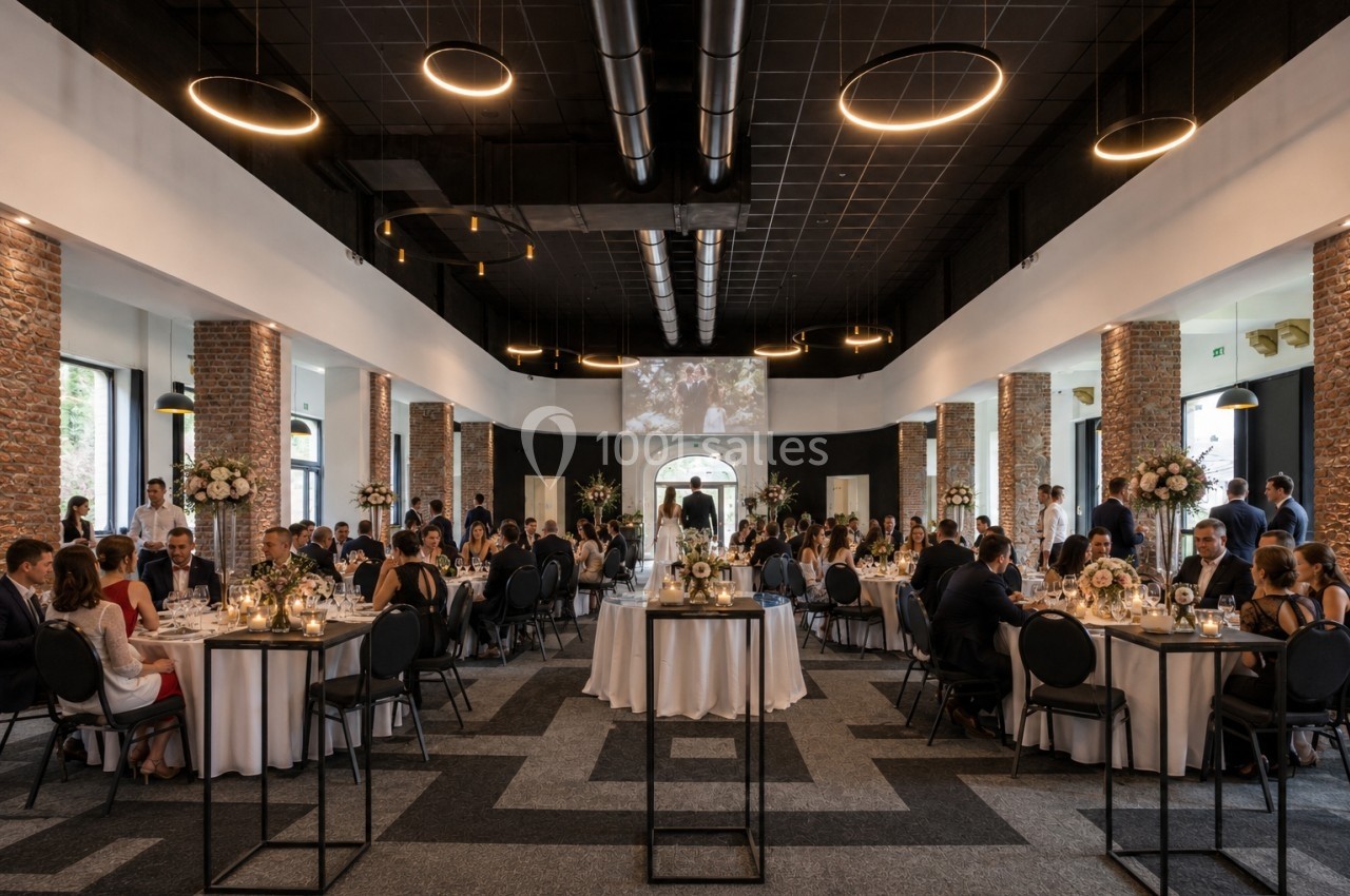 Salle de réception élégante avec invités assis à des tables décorées, éclairée par des luminaires modernes.