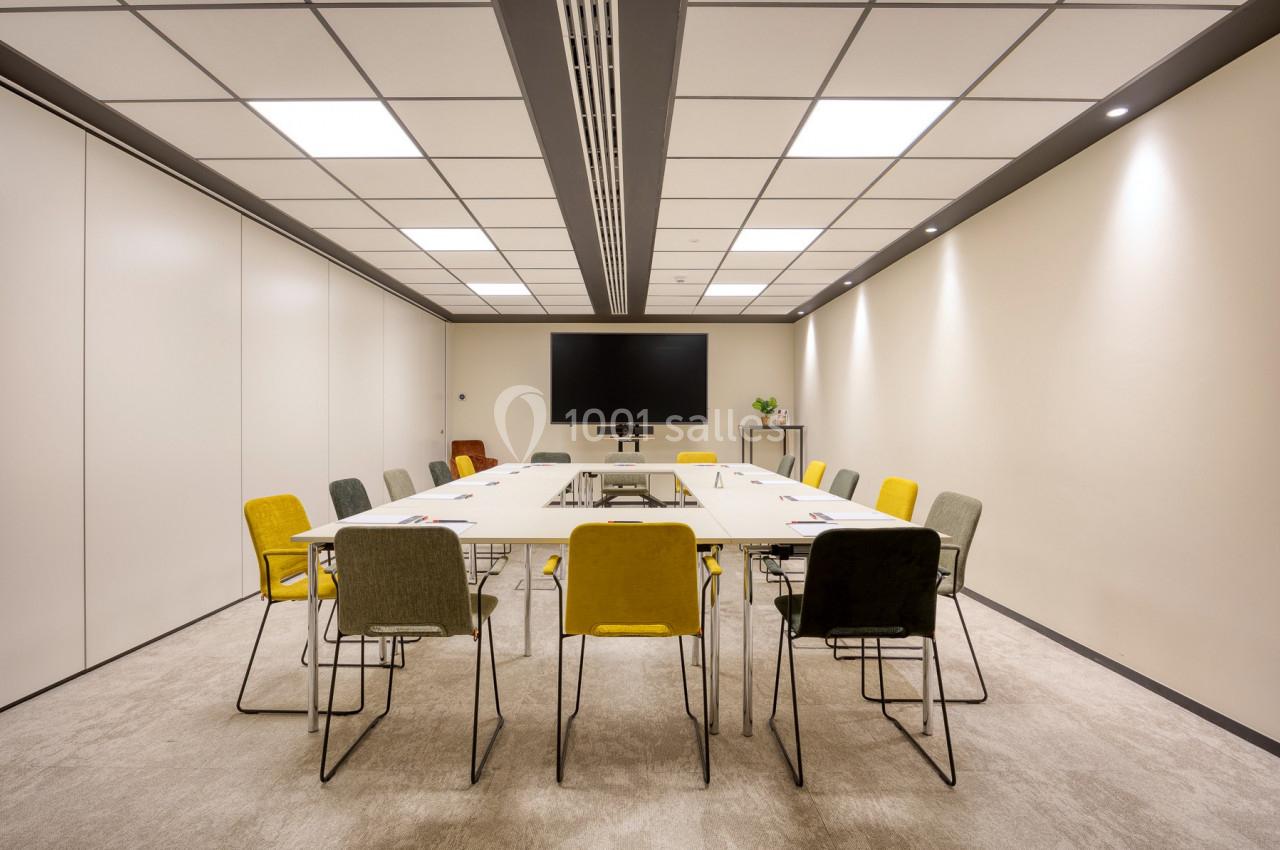 Location salle Namur (Namur) - Casino Resort Namur #6 Salle de réunion moderne avec table rectangulaire, chaises colorées, écran mural et éclairage au plafond.