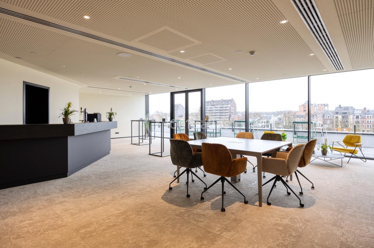 Location salle Namur (Namur) - Casino Resort Namur #9 Salle de réunion lumineuse avec table, chaises colorées et grandes baies vitrées donnant sur un paysage urbain.