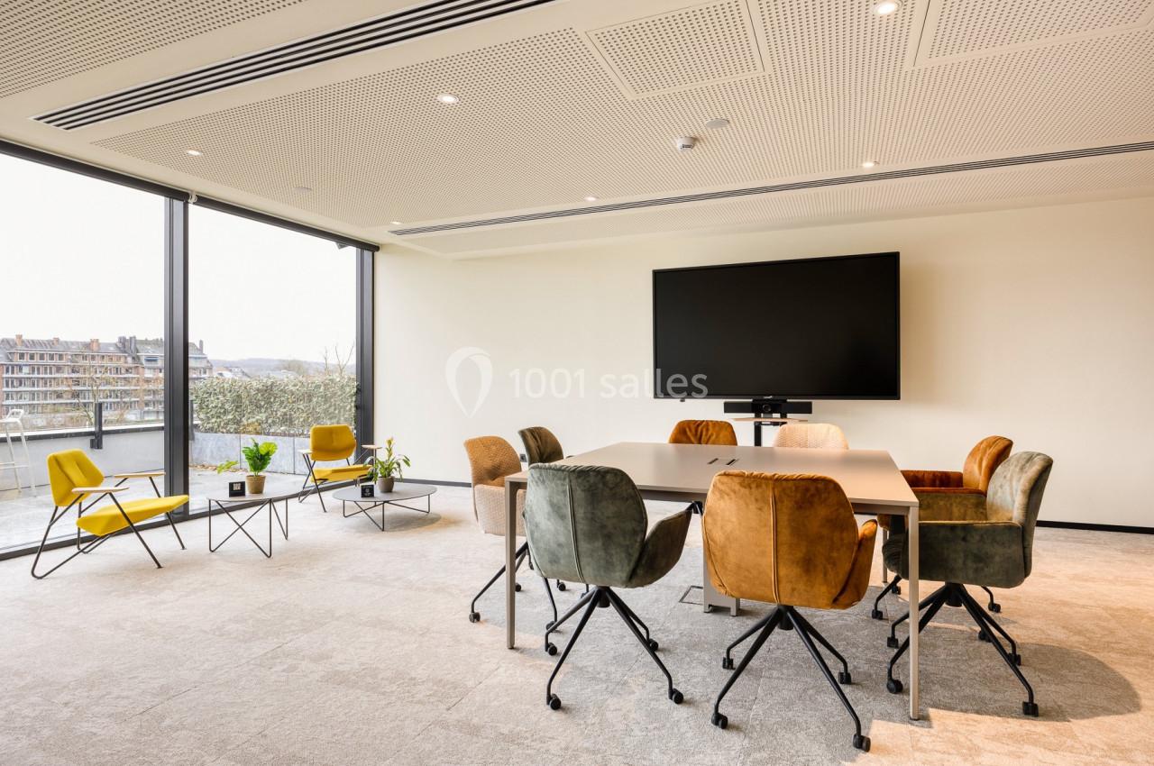 Location salle Namur (Namur) - Casino Resort Namur #10 Salle de réunion lumineuse avec table, chaises colorées, écran mural et grandes baies vitrées donnant sur l'extérieur.