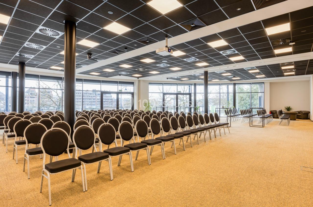 Location salle Namur (Namur) - Casino Resort Namur #21 Salle de conférence lumineuse avec des rangées de chaises noires alignées et de grandes baies vitrées donnant sur l…