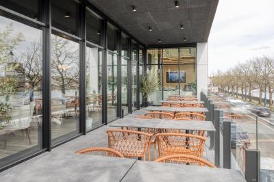 Miniature Location salle Namur (Namur) - Casino Resort Namur #34 Terrasse moderne avec mobilier vert et blanc, vue sur une rivière et des bâtiments en arrière-plan.