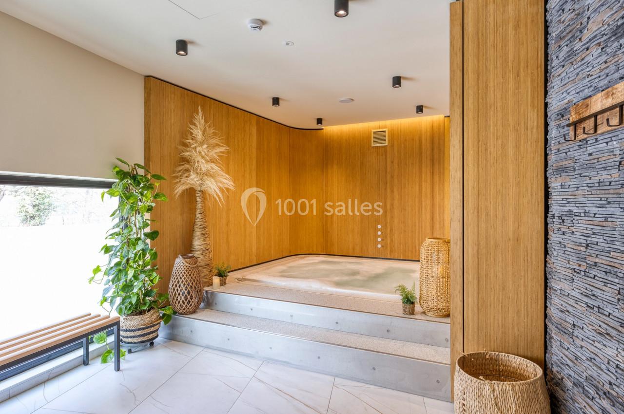 Location salle Namur (Namur) - Casino Resort Namur #35 Bain à remous encastré dans une pièce au design naturel avec murs en bois, plantes et lumière douce.