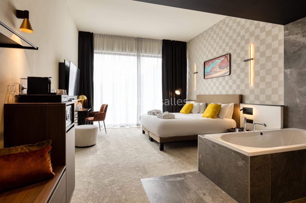 Location salle Namur (Namur) - Casino Resort Namur #43 Chambre d'hôtel moderne avec lit double, baignoire intégrée, bureau, télévision et grande baie vitrée.