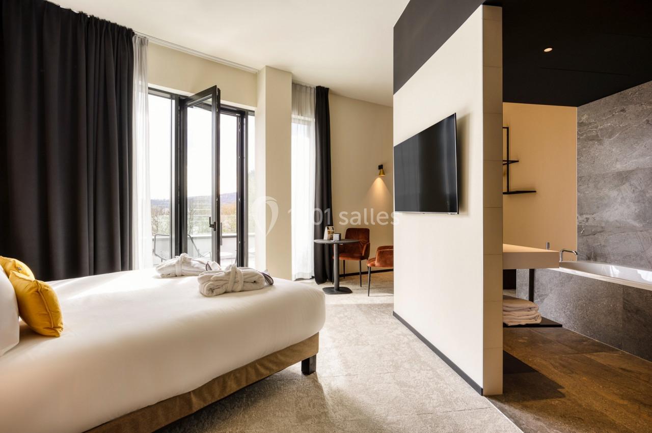 Location salle Namur (Namur) - Casino Resort Namur #48 Chambre d'hôtel lumineuse avec lit double, télévision murale, salle de bain attenante et balcon avec vue extérieure.