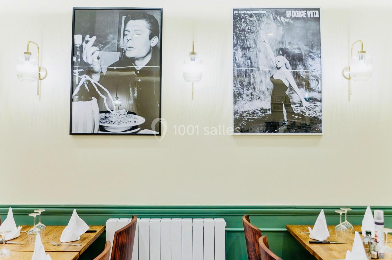 Deux affiches en noir et blanc décorent un mur au-dessus de tables dressées dans un restaurant.