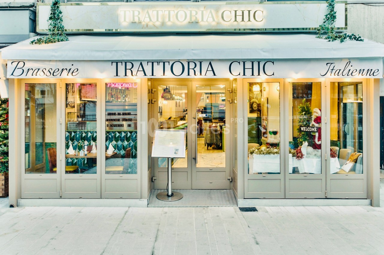 Façade d'un restaurant italien avec terrasse couverte, enseigne ’Trattoria Chic’ et menu affiché à l'entrée.
