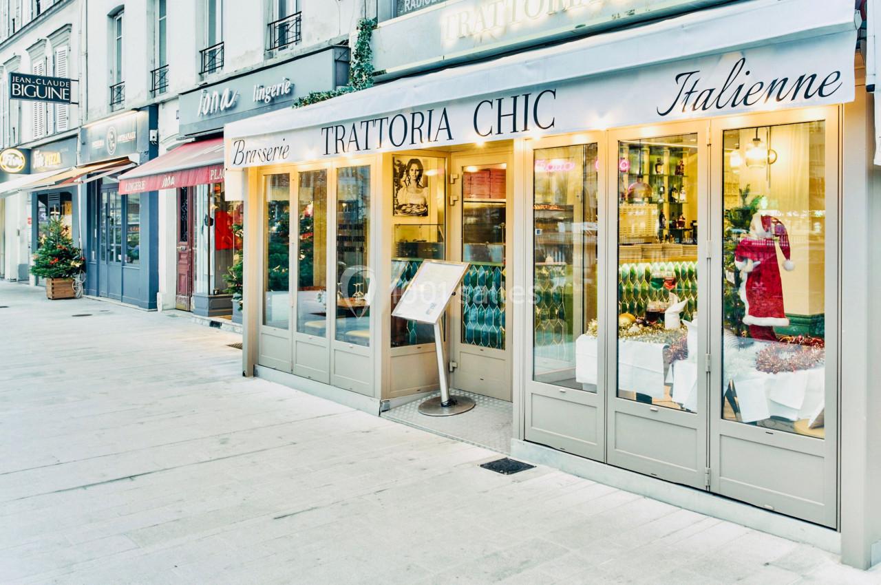 Façade d'un restaurant italien avec vitrines éclairées, menu extérieur et décorations de Noël sur le trottoir.