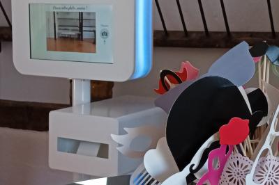 Borne photo interactive avec accessoires colorés disposés dans un pot sur une table, décor en arrière-plan.