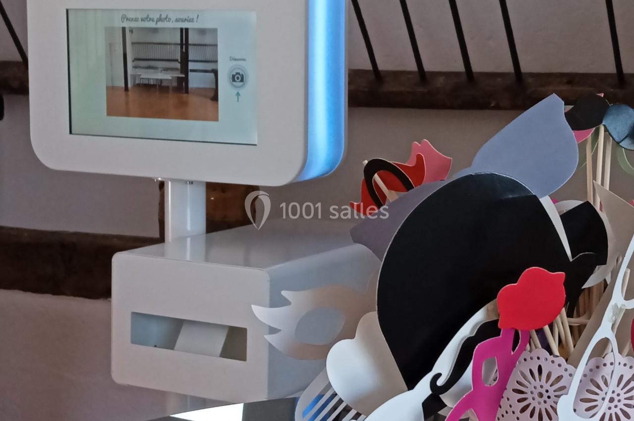 Borne photo interactive avec accessoires colorés disposés dans un pot sur une table, décor en arrière-plan.