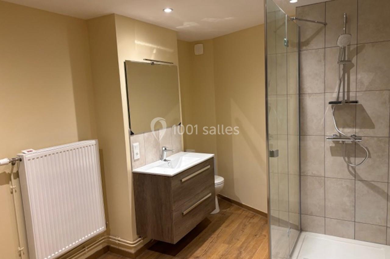 Salle de bain moderne avec parquet, douche à l'italienne, meuble lavabo avec miroir et radiateur mural.