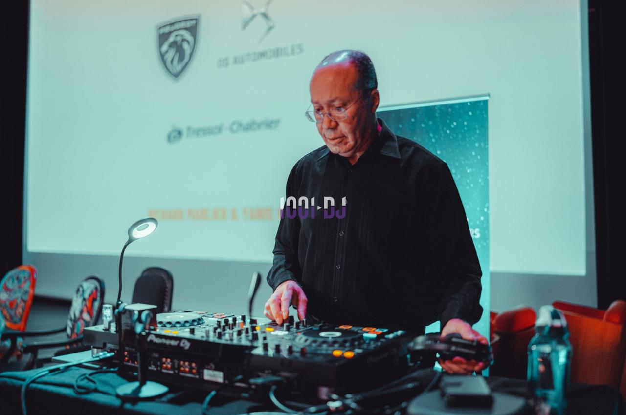 Un homme utilise une table de mixage dans une salle équipée d'un écran de projection en arrière-plan.
