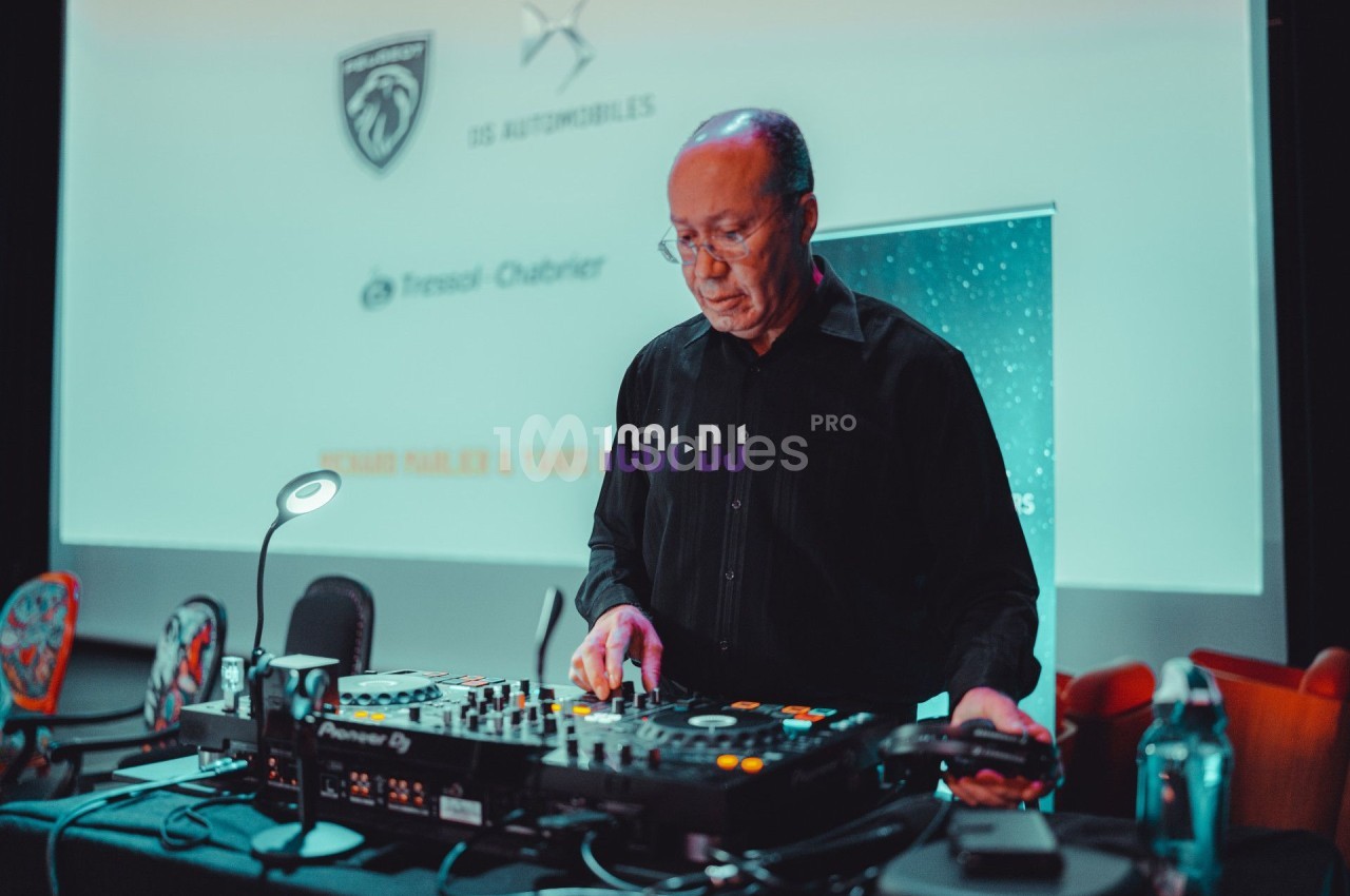Un homme utilise une table de mixage dans une salle équipée d'un écran de projection en arrière-plan.