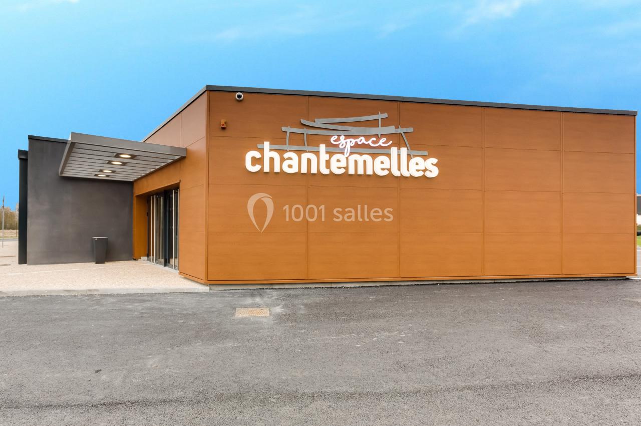 Façade d'un bâtiment moderne avec revêtement en bois et enseigne ’Espace Chantemelles’ sur un parking asphalté.