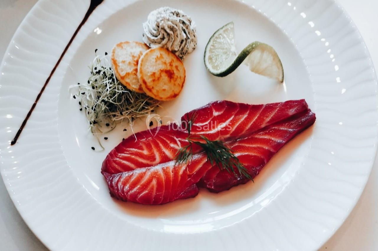Assiette de saumon fumé avec herbes, rondelles de pommes de terre, mousse, germes et quartier de citron vert.