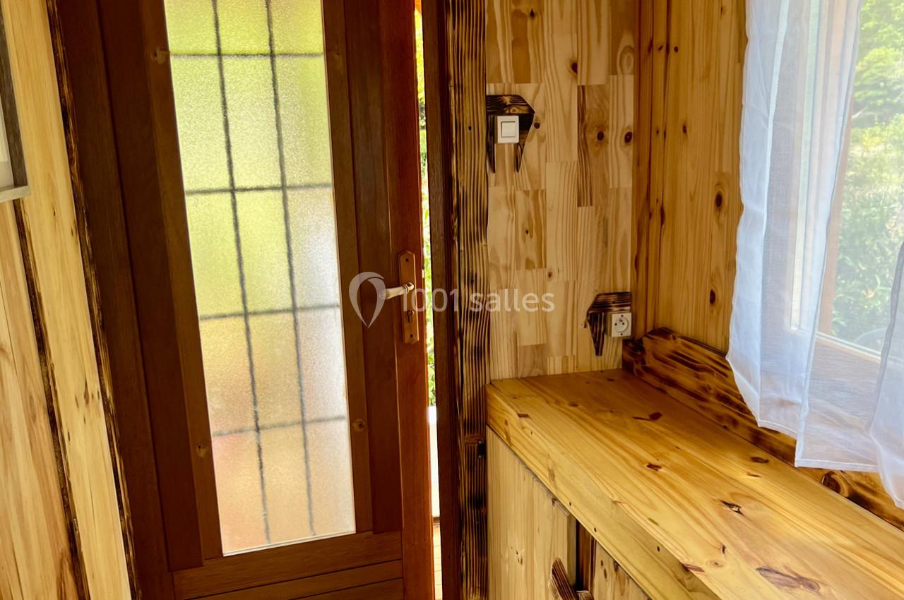 Intérieur en bois clair avec une porte vitrée, un plan de travail et une fenêtre laissant entrer la lumière naturelle.