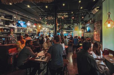 Miniature Location salle Lille (Nord) - Barnett's #4 Deux personnes souriantes dans un café à l'ambiance chaleureuse, avec un mur en briques et une enseigne néon.