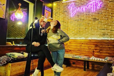 Miniature Location salle Lille (Nord) - Barnett's #13 Deux personnes souriantes dans un café à l'ambiance chaleureuse, avec un mur en briques et une enseigne néon.