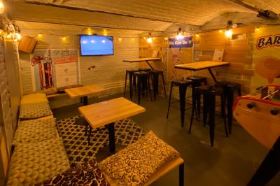 Miniature Notre cave privative. Deux personnes souriantes dans un café à l'ambiance chaleureuse, avec un mur en briques et une enseigne néon.