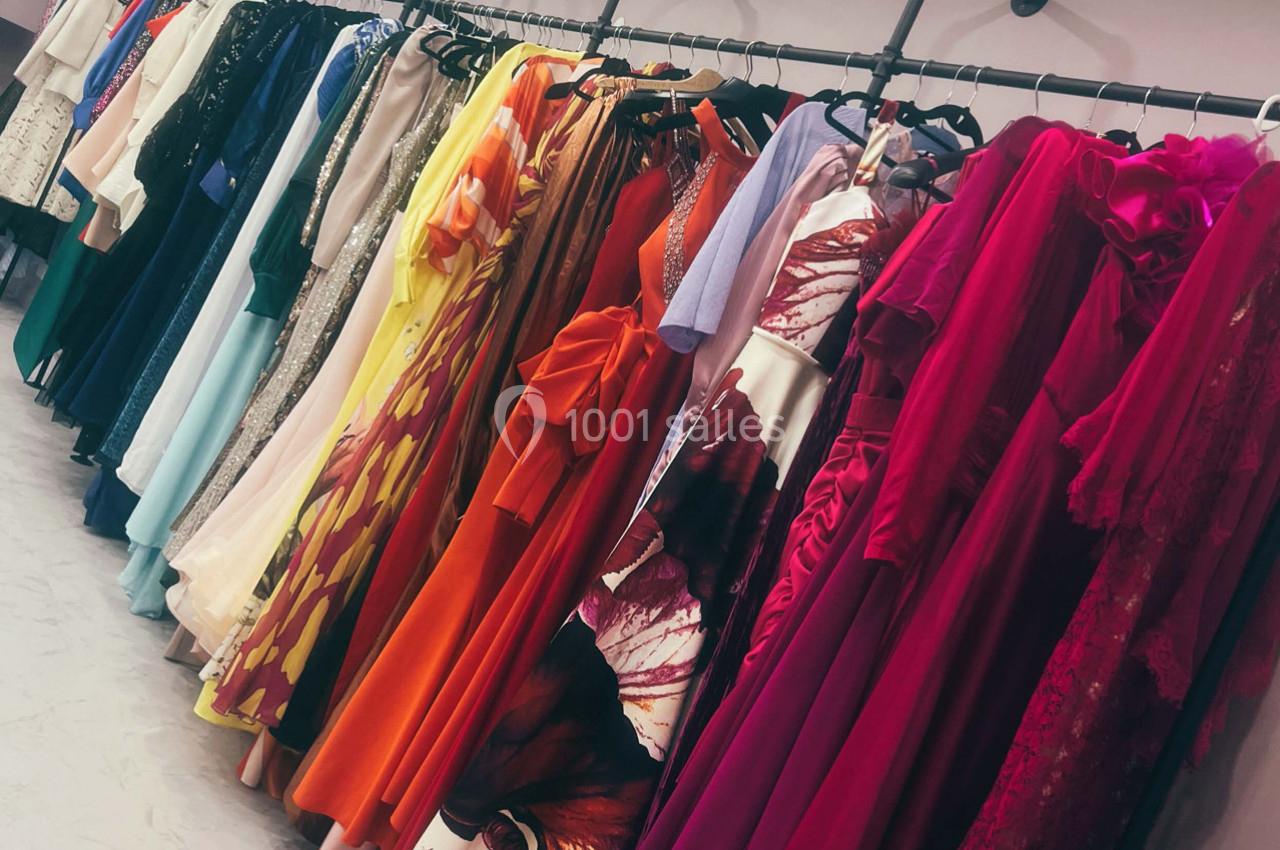 Robes colorées et élégantes suspendues sur des cintres dans une boutique ou un dressing.