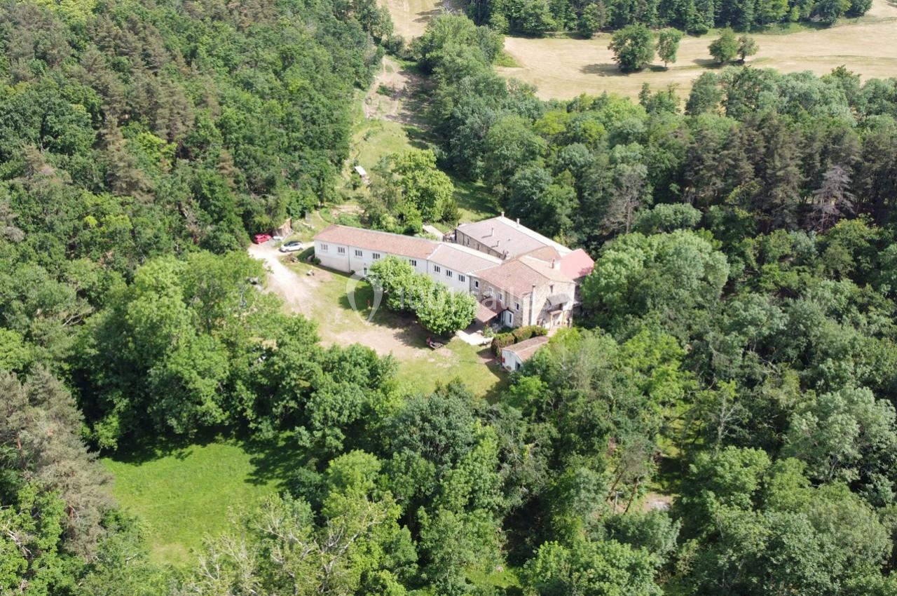 Vue aérienne d'un grand bâtiment entouré de forêt et de clairières verdoyantes.