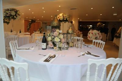 Miniature Location salle Noisy-le-Grand (Seine-Saint-Denis) - Espace du Mont d'Est #10 Centre de table floral avec roses et feuillage, entouré de tables dressées dans une salle lumineuse.