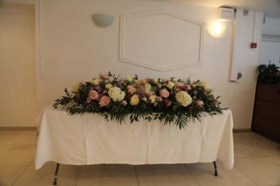 Miniature Location salle Noisy-le-Grand (Seine-Saint-Denis) - Espace du Mont d'Est #6 Centre de table floral avec roses et feuillage, entouré de tables dressées dans une salle lumineuse.