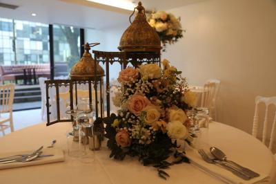 Miniature Location salle Noisy-le-Grand (Seine-Saint-Denis) - Espace du Mont d'Est #15 Centre de table floral avec roses et feuillage, entouré de tables dressées dans une salle lumineuse.