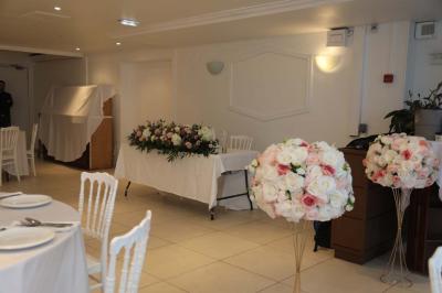 Miniature Location salle Noisy-le-Grand (Seine-Saint-Denis) - Espace du Mont d'Est #5 Centre de table floral avec roses et feuillage, entouré de tables dressées dans une salle lumineuse.