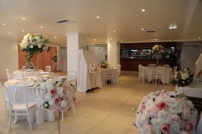 Miniature Location salle Noisy-le-Grand (Seine-Saint-Denis) - Espace du Mont d'Est #9 Centre de table floral avec roses et feuillage, entouré de tables dressées dans une salle lumineuse.