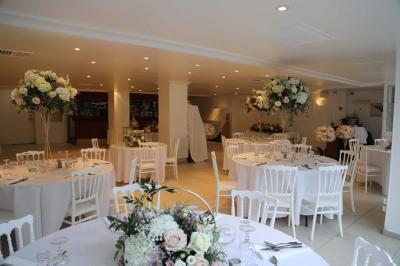 Miniature Location salle Noisy-le-Grand (Seine-Saint-Denis) - Espace du Mont d'Est #19 Centre de table floral avec roses et feuillage, entouré de tables dressées dans une salle lumineuse.