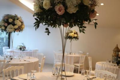 Miniature Location salle Noisy-le-Grand (Seine-Saint-Denis) - Espace du Mont d'Est #21 Centre de table floral avec roses et feuillage, entouré de tables dressées dans une salle lumineuse.