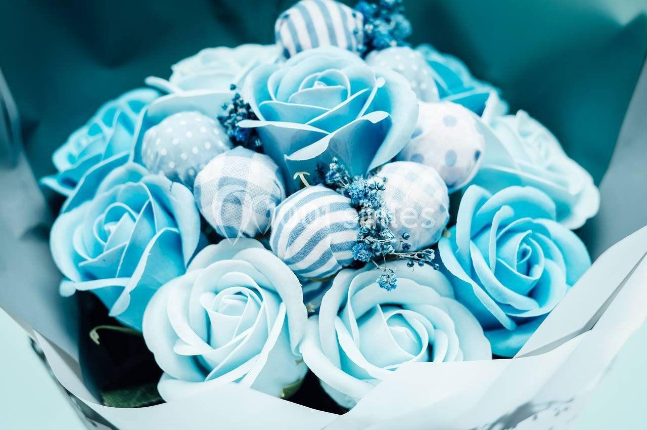Bouquet de roses bleues accompagné de décorations en tissu à motifs dans des tons assortis.