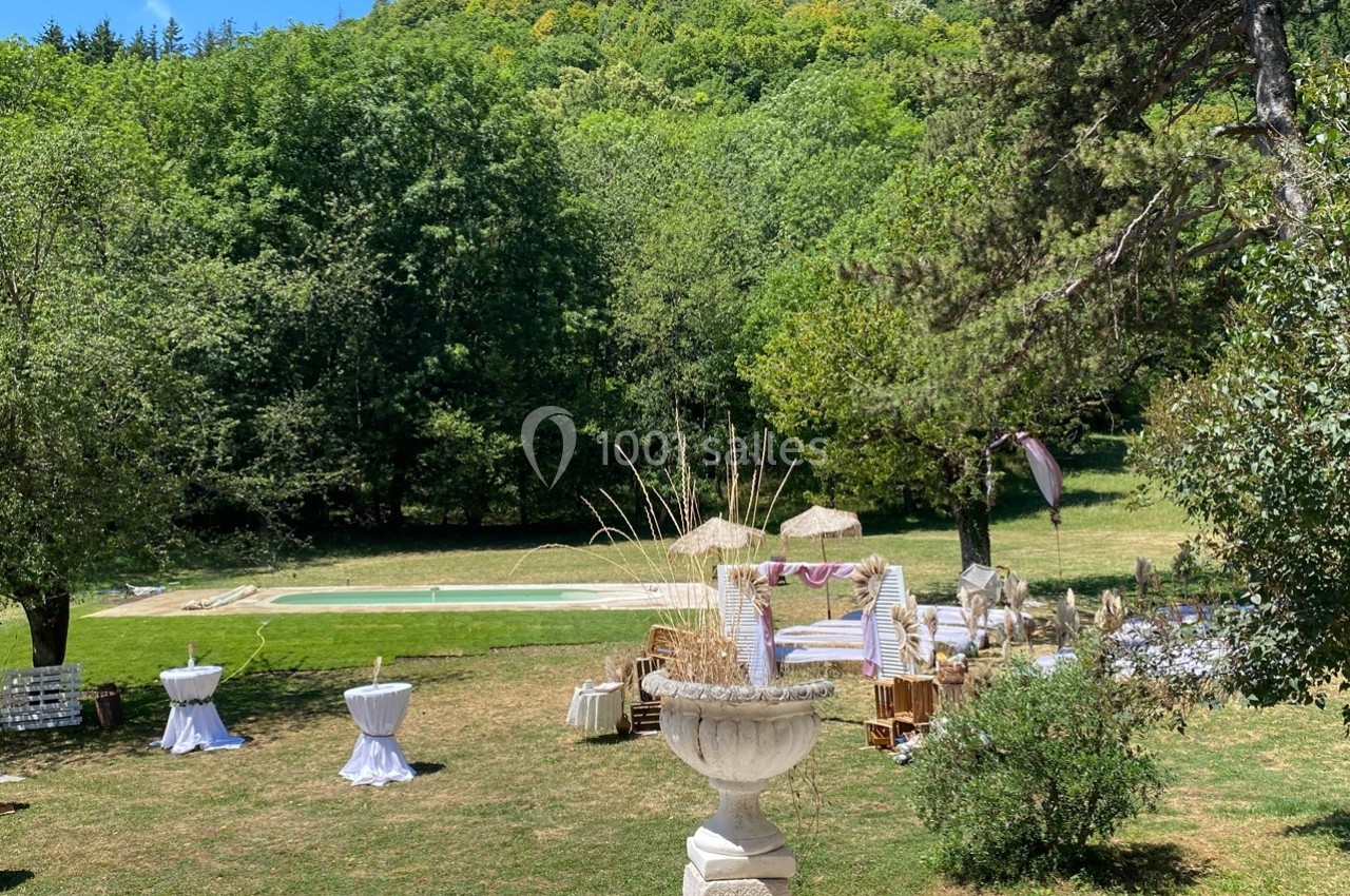 Espace extérieur avec piscine, mobilier de jardin et décorations, entouré de verdure et d'arbres.