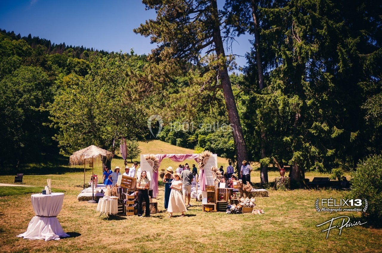 Groupe de personnes rassemblées dans un jardin ensoleillé avec des décorations et des stands en bois.