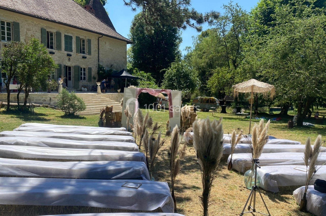 Chaises alignées en extérieur devant une maison ancienne, décorées pour un événement avec des herbes de la pampa.