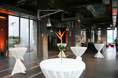 Miniature Le rez-de-chaussée Salle lumineuse avec de grandes baies vitrées, tables dressées avec nappes grises, vaisselle et décoration florale.