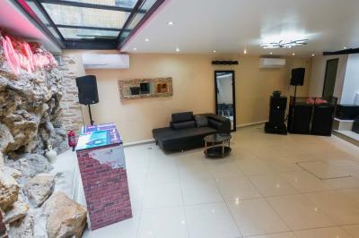 Cuisine moderne avec îlot central noir, chaises hautes, meubles rouges, électroménagers intégrés et carrelage blanc.