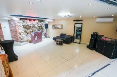 Cuisine moderne avec îlot central noir, chaises hautes, meubles rouges, électroménagers intégrés et carrelage blanc.