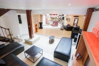 Cuisine moderne avec îlot central noir, chaises hautes, meubles rouges, électroménagers intégrés et carrelage blanc.