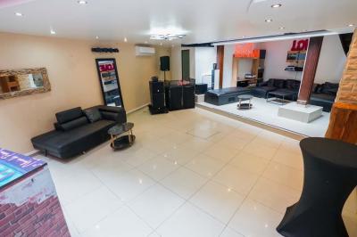 Cuisine moderne avec îlot central noir, chaises hautes, meubles rouges, électroménagers intégrés et carrelage blanc.