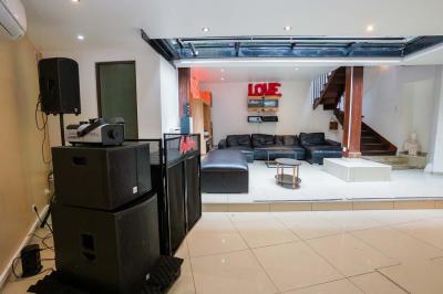 Cuisine moderne avec îlot central noir, chaises hautes, meubles rouges, électroménagers intégrés et carrelage blanc.