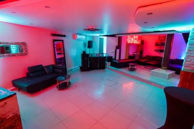 Cuisine moderne avec îlot central noir, chaises hautes, meubles rouges, électroménagers intégrés et carrelage blanc.